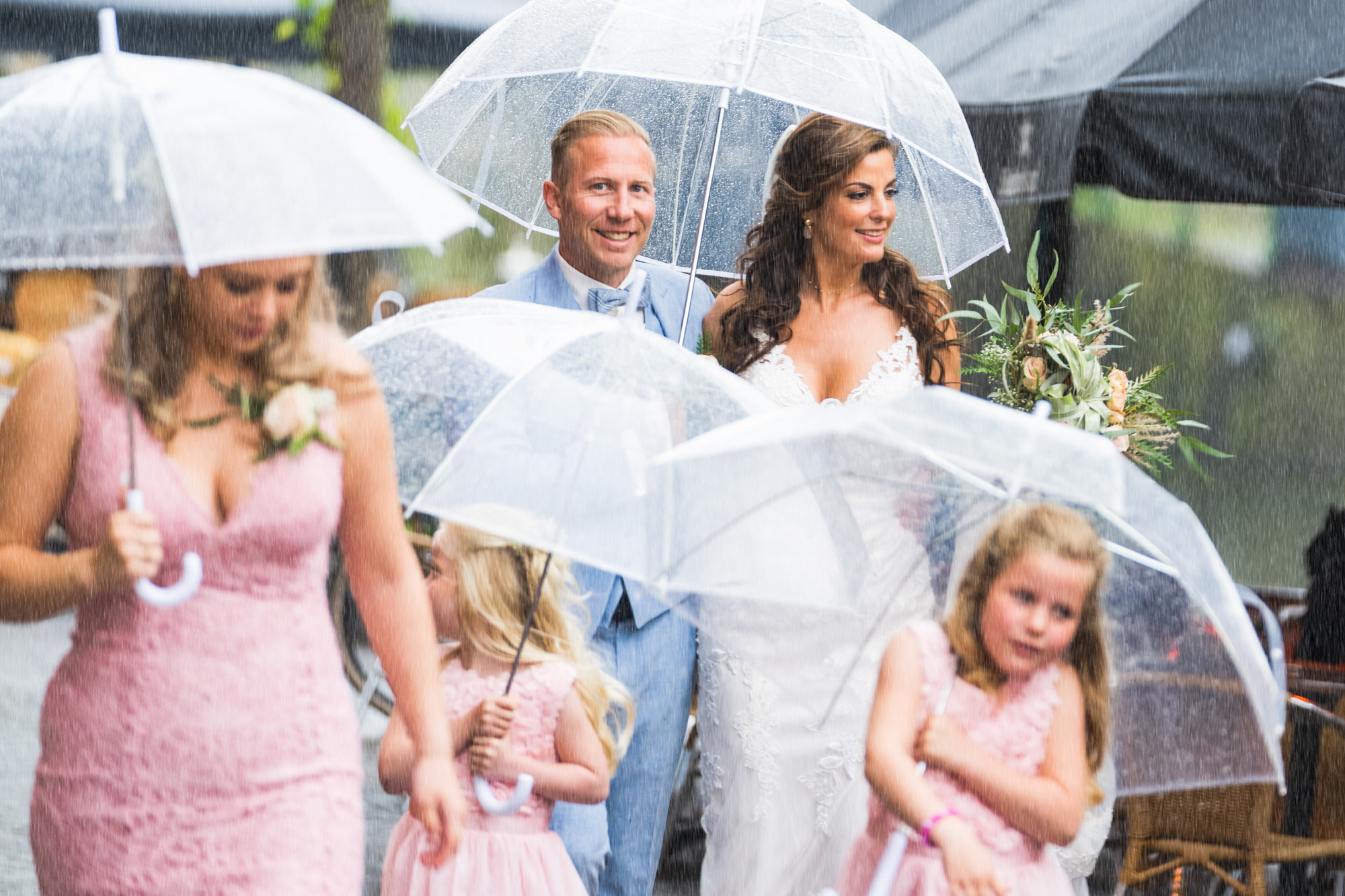 bruidspaar met kinderen in de regen