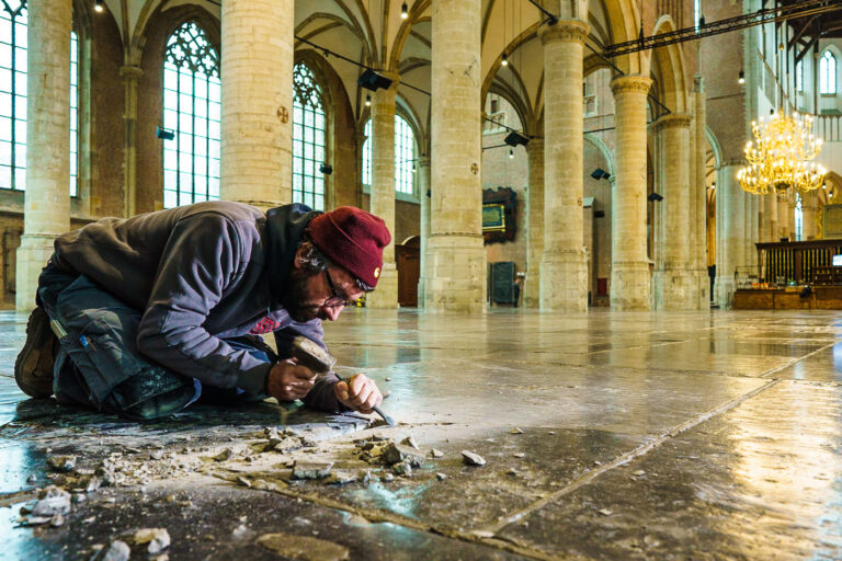 Steenhouwers repareren en onderhouden de eeuwenoud vloer van de kerk.
