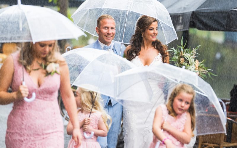 bruidspaar met kinderen in de regen